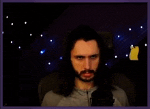 a man with long hair and a mustache is making a funny face while sitting in front of a microphone .
