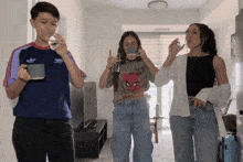 a boy wearing an adidas shirt is drinking from a mug