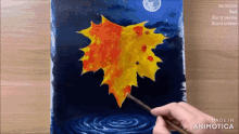 a person is painting a maple leaf on a canvas that is made in animatica