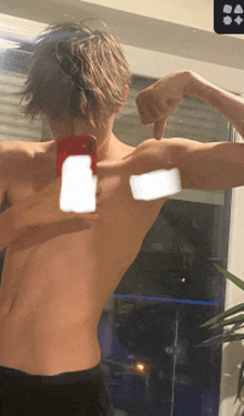 a shirtless man is taking a picture of his back with his phone