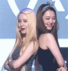 two young women are standing back to back and smiling .