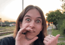 a woman with long hair is making a funny face with her hands .