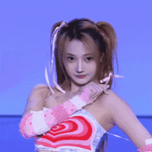 a woman with pigtails is holding a pink doll in her hand .
