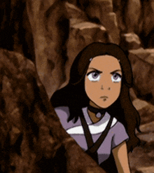 a girl in a purple shirt is standing in a rocky area