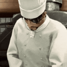 a man wearing a chef 's hat and glasses is standing in a kitchen .