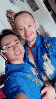 two men wearing blue shirts are posing for a picture and one of them has a tiktok sticker on his face