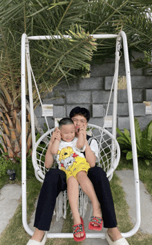 a man and child are sitting on a white swing