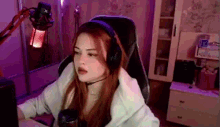 a woman wearing headphones and a microphone is sitting in front of a computer screen .