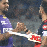 a man in a purple shirt shakes hands with another man in a red shirt