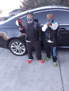 two young boys standing in front of a car with one wearing a vest that says havoc on it