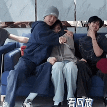 a group of people are sitting on a blue couch and one of them is hugging another person