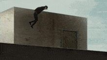 a silhouette of a person standing on the edge of a building with a green door