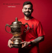 a man in a red shirt is holding a trophy and smiling