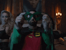 a man in a robin costume is putting on a green mask over his eyes