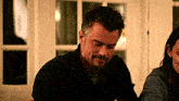 a man with a beard sits next to a woman in a dark room