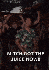 a man in a hawaiian shirt is dancing in front of a crowd of people .