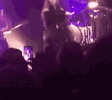 a woman is dancing on a stage in front of a crowd while a drummer plays drums .