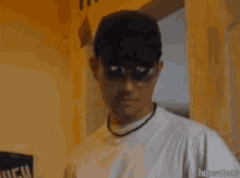 a man wearing sunglasses and a baseball cap is standing in a room .