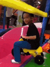 a young boy is riding a toy car on a slide .