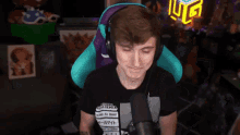 a man wearing headphones and a black shirt is sitting in front of a microphone in a room .