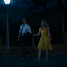 a man and a woman walking down a street at night