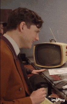 a man sitting in front of an old fashioned tv