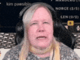 a woman wearing headphones is sitting in front of a screen that says " kim pawsible "
