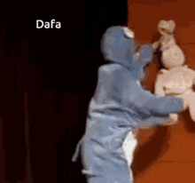 a person in a shark costume is holding a stuffed animal and says dafa .