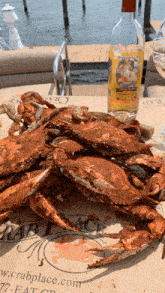 a pile of crabs sits on a table next to a bottle of preserves wine