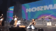a woman is kneeling on the floor on a stage in front of a sign that says normal