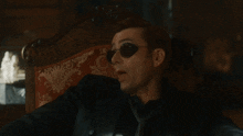 a man wearing sunglasses and a black shirt is sitting in a chair