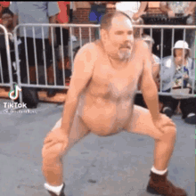 a shirtless man is dancing in front of a crowd of people .