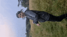 a man in a black jacket is standing in a field