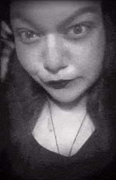 a black and white photo of a woman 's face with a necklace around her neck .