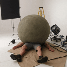 a man is laying on the floor with a large ball on top of his head