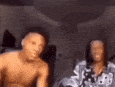 a man without a shirt is sitting next to a woman without a shirt