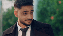 a man with a beard wearing a suit and tie with the word inshot on the bottom right