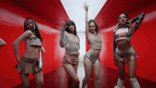 four women are dancing in a room with a red wall