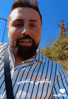 a man with a beard is wearing a striped shirt and has a heart in the lower right corner