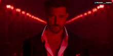 a man in a suit and white shirt stands in front of a red background that says pranay varma on it