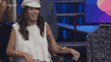 a woman with a tattoo on her arm is wearing a hat and a white shirt