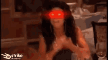 a woman is sitting at a table with a red light shining on her face .