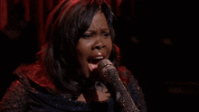 a woman singing into a microphone in front of a crowd