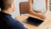 a man and a woman are sitting at a table with a laptop