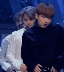 a group of men are standing next to each other on a stage and one of them is holding the other 's waist .