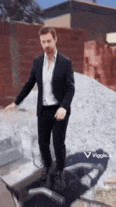 a man in a suit is standing in front of a pile of rocks .