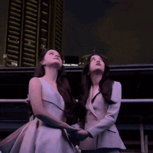 two women looking up at a skyscraper at night