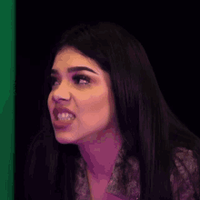 a close up of a woman making a funny face in front of a green background .