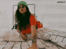 a woman wearing a green hat is laying on a bed