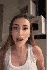 a woman in a white tank top is talking